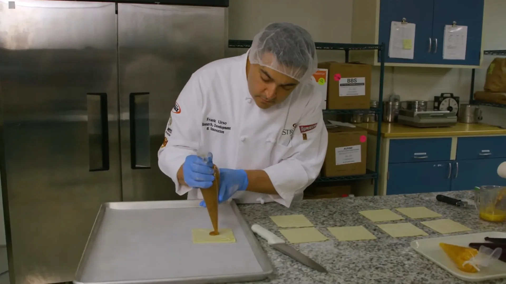 A chef carefully pipes a pastry filling in a commercial kitchen.